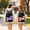 Two girls wearing matching pink and purple nylon school backpacks walking outdoors.