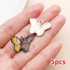 A set of five colorful butterfly enamel charms displayed on a person's hand.
