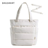 Sac cabas matelassé blanc avec poignée longue et tirette à zip sur fond blanc.