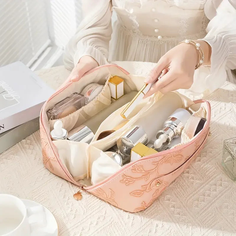 A light pink vintage floral waterproof makeup tote bag is open, showing various cosmetic bottles and skincare products.