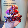 A hand holds a red and blue balloon dog keychain charm with a purple tag.