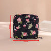 Black pouch with pink floral and flamingo patterns for storing sanitary pads or tampons