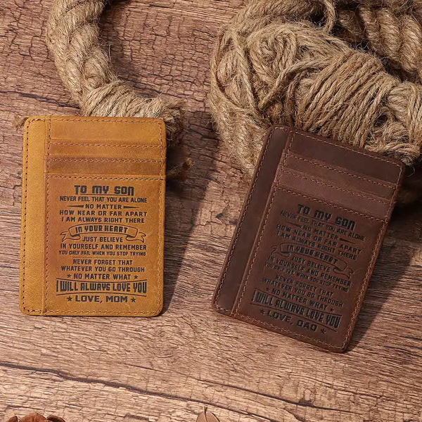 A brown leather card wallet with engraved text To my son and love mom dad resting on a wooden surface.
