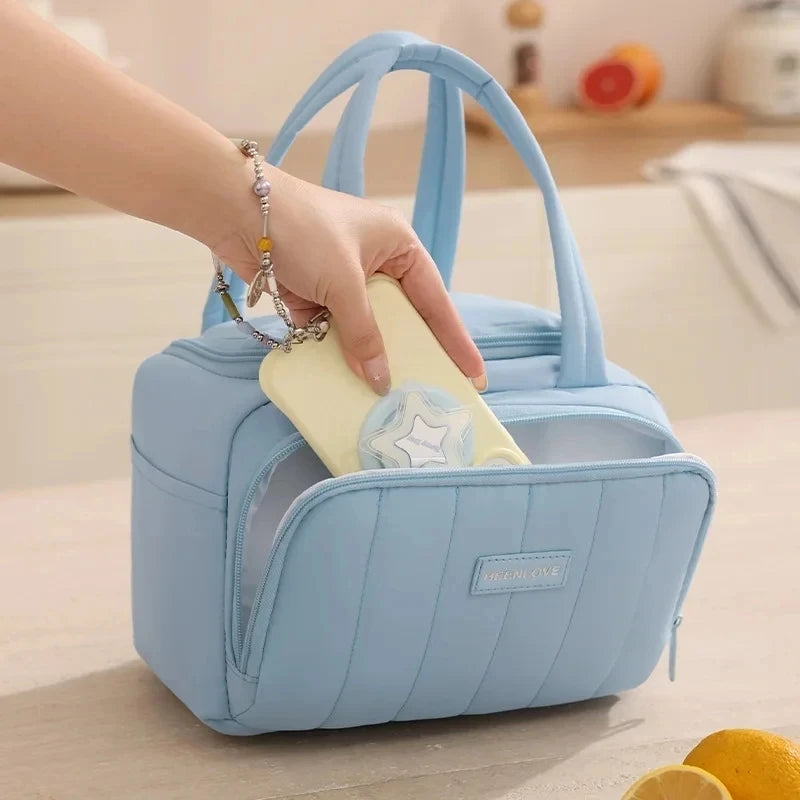 Una mano está colocando un collar de plata en el bolsillo de una bolsa térmica acolchada azul claro.