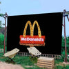 A large black banner featuring the McDonald's golden arches logo with bright lights, set outdoors.