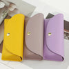 A set of three PU leather hard shell sunglasses cases in yellow, mauve, and purple.