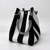 A black and white striped retro knitted bucket handbag with silver hardware.