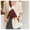 A woman models a brown leather Rivet waist bag crossbody fanny pack with gold hardware and a beige blazer.