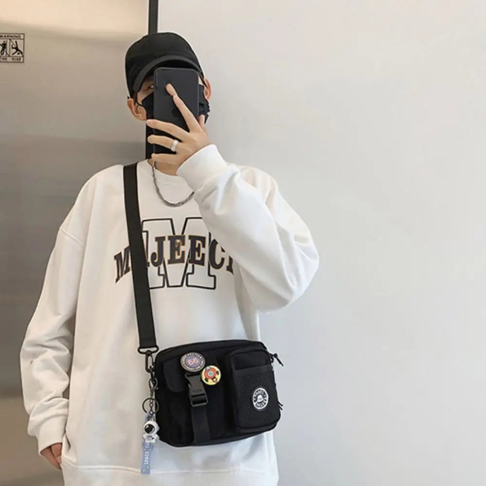 A woman wearing a white hoodie and black cap holds a black canvas shoulder bag.