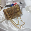 A gold rhinestone leather evening clutch bag is displayed on white satin fabric.