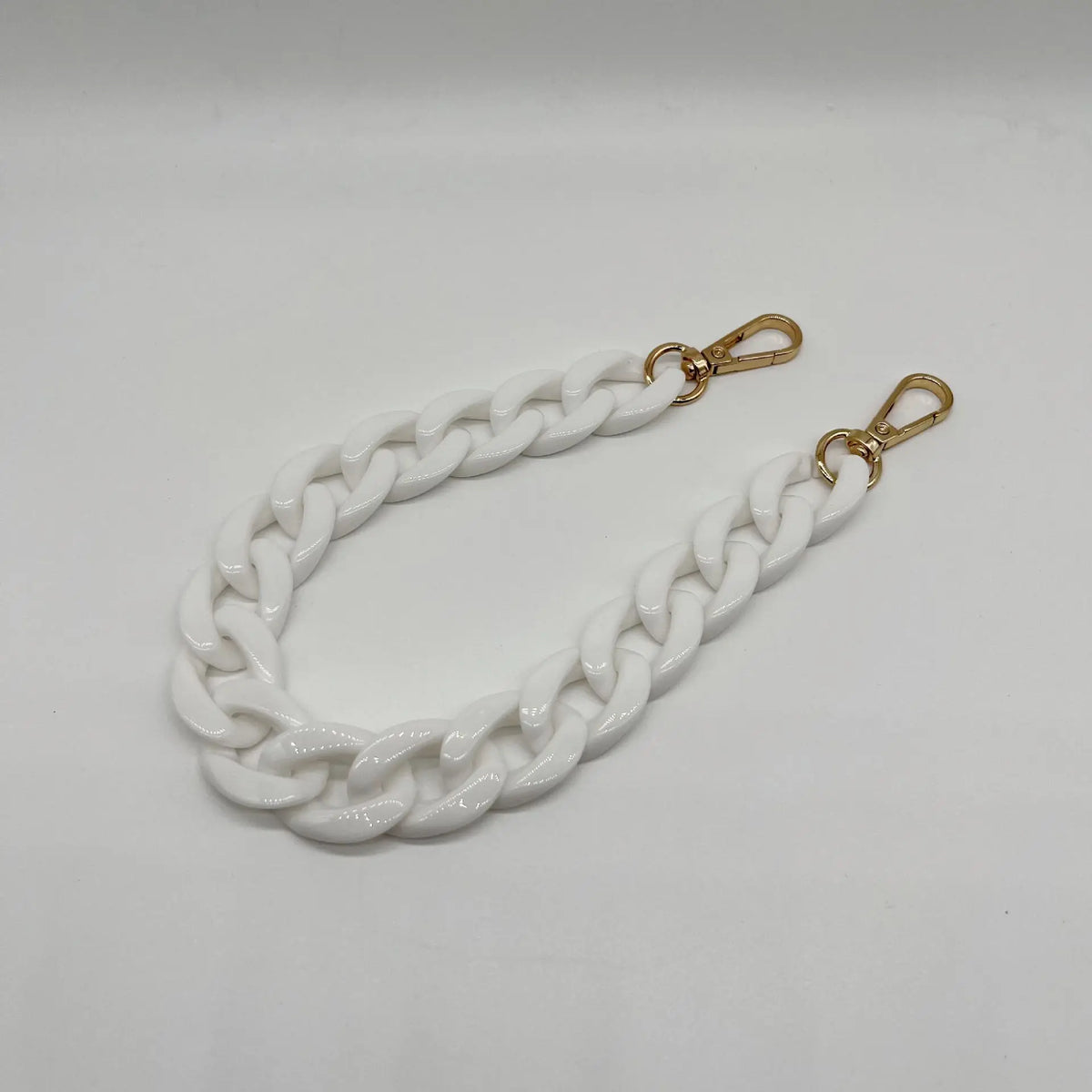 A white acrylic chain bracelet with gold-toned clasps.