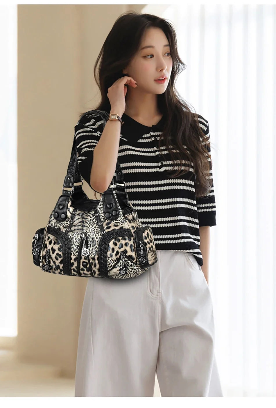 A woman models a black and white striped top and light pants while holding a leopard print PU leather tote bag.
