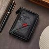 A black vintage PU leather slim wallet with an embossed K and a leather pen resting on a dark surface.