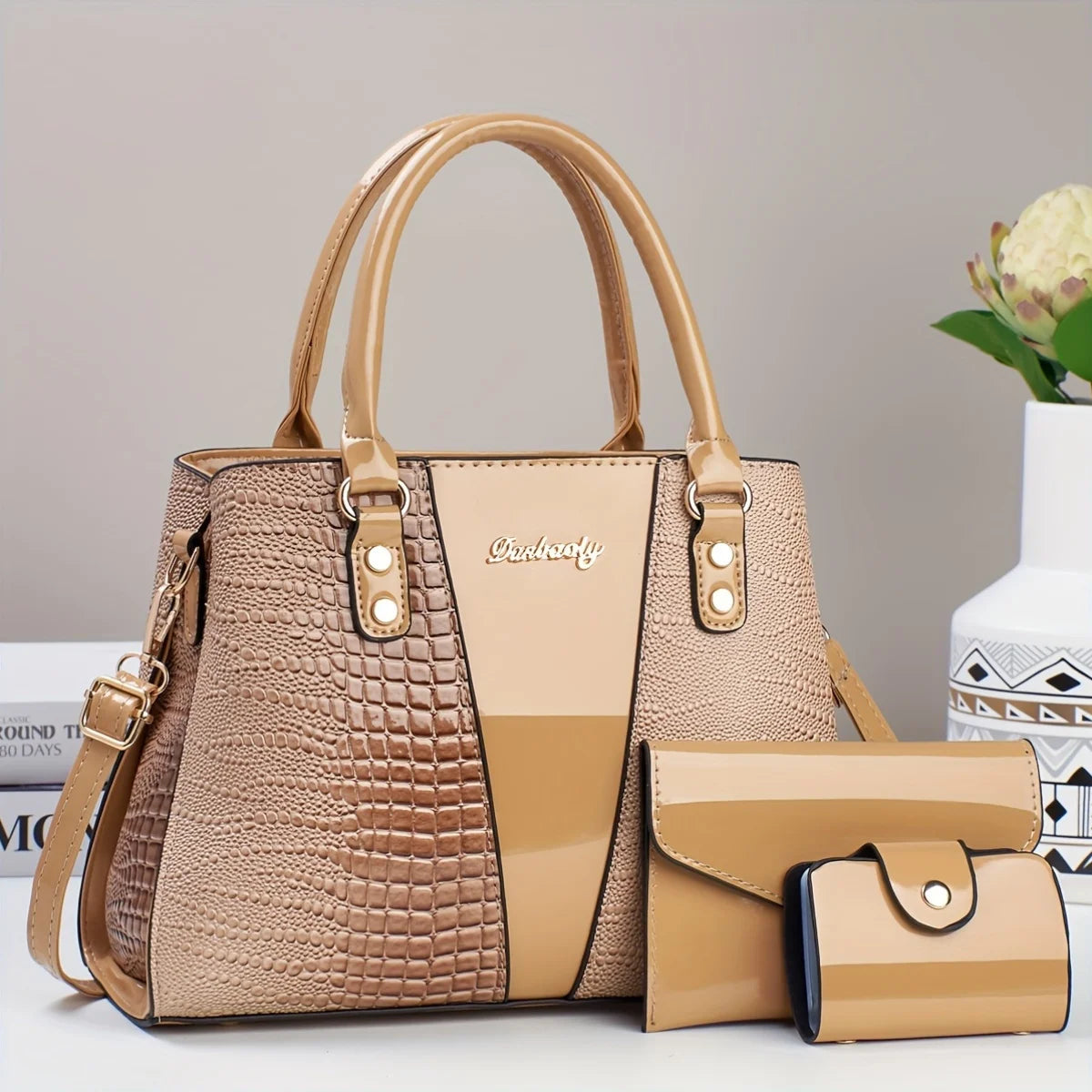 Bolso y cartera de cuero de cocodrilo beige exhibidos sobre una superficie blanca.