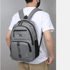 A man wearing a white shirt and khaki pants is shown carrying a gray lightweight commuter backpack.