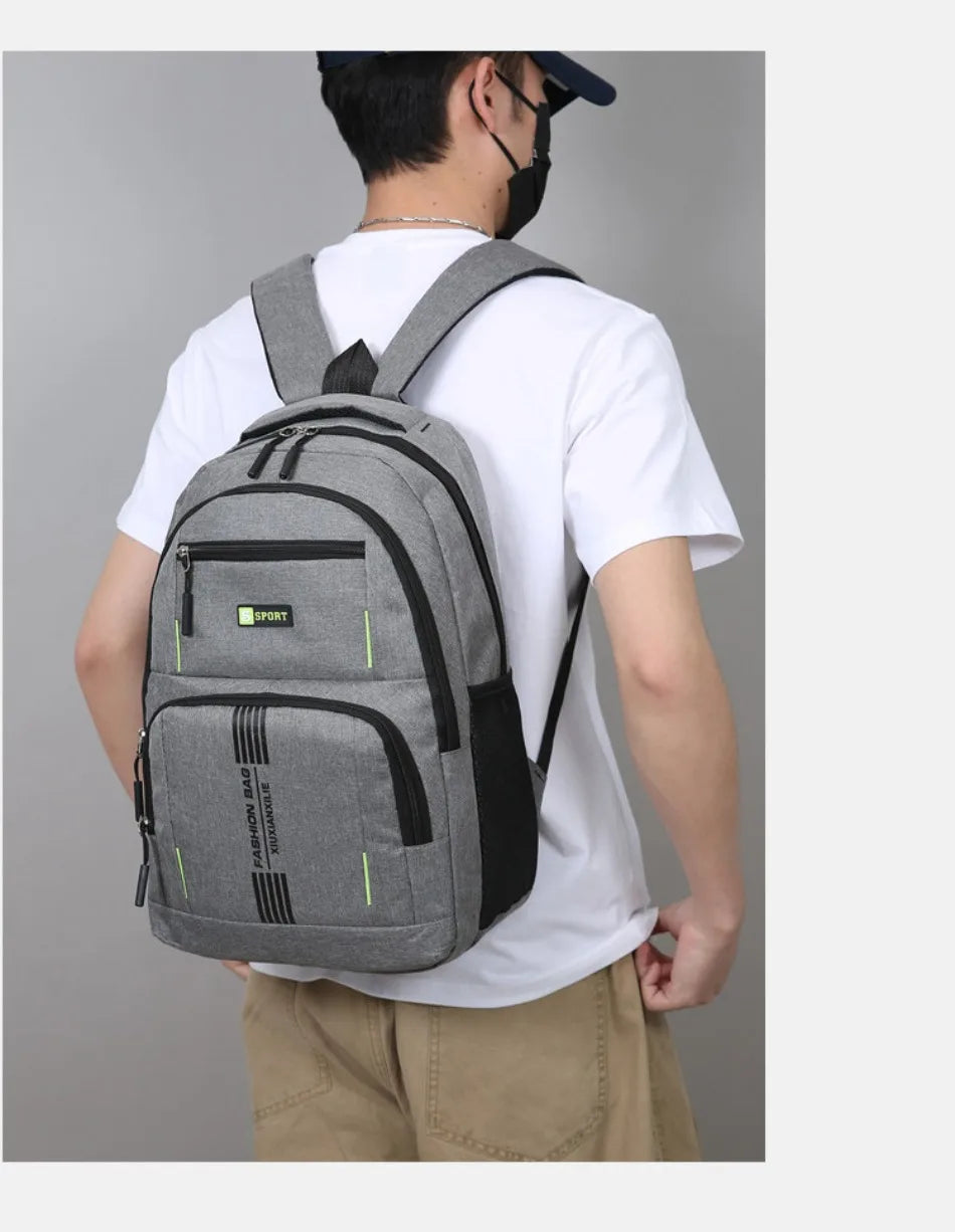 A man wearing a white shirt and khaki pants is shown carrying a gray lightweight commuter backpack.