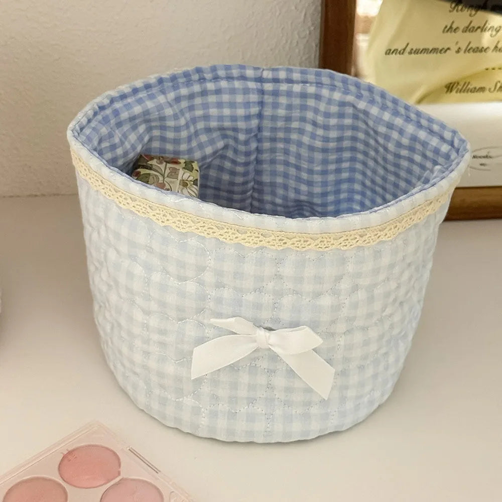 Cesta de guardado de tela de acolchado a cuadros azul claro y blanco con lazo de cinta blanca.