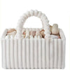 A white flannel diaper caddy organizer filled with baby items and topped with a fluffy handle.