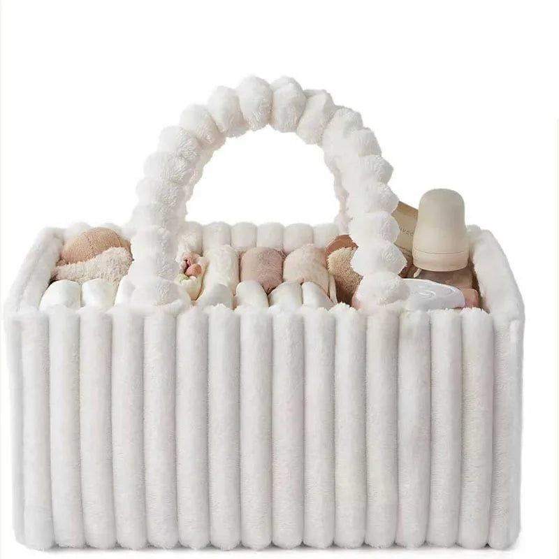 A white flannel diaper caddy organizer filled with baby items and topped with a fluffy handle.