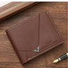 A brown men's slim leather bi-fold wallet resting on a wooden surface next to a pen.