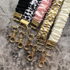 Präsentation eleganter goldener Schlüsselanhänger und Lanyards in gestreiften Farben wie schwarz, weiß, rosa und gold.