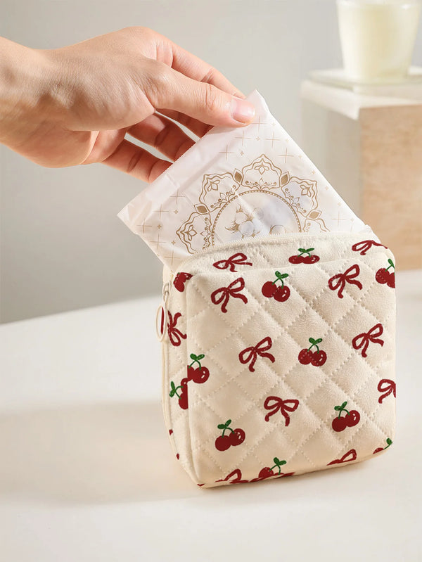 A hand holds a quilted storage pouch with a cherry and bow print, showing the fabric texture and design.