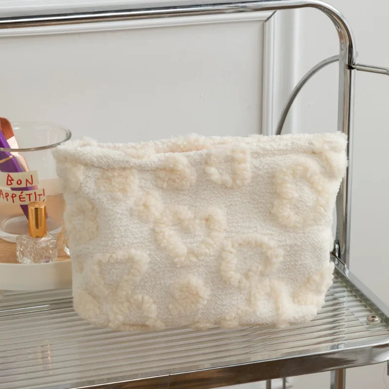 A fluffy cream colored storage bag with a heart pattern resting on a metal shelf.