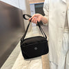 Una persona sostiene un bolso cruzado de nylon impermeable negro en un tono claro.