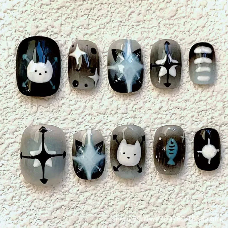 A set of press-on nails featuring cute cartoon animal designs like a cat and a fish on a white background.