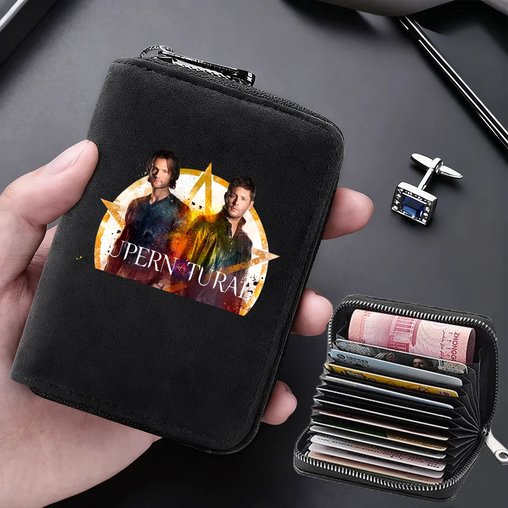 A black compact RFID-blocking card wallet with 11 slots is held in a hand, featuring a graphic of two men.
