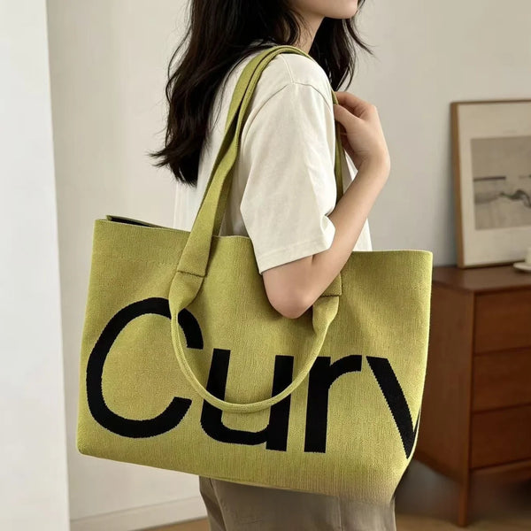 A woman holds a lime green knitted large tote bag with a black strap.