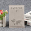 Housse de passeport en cuir PU beige, gravée d'une carte du monde et d'un avion, posée sur une surface grise.