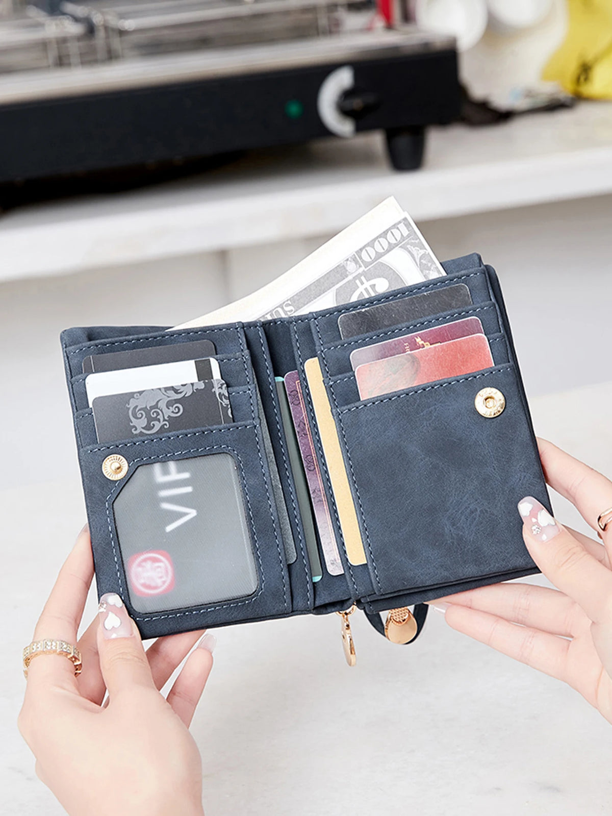A hand holds a dark blue PU leather double fold wallet with various cards and cash inside.