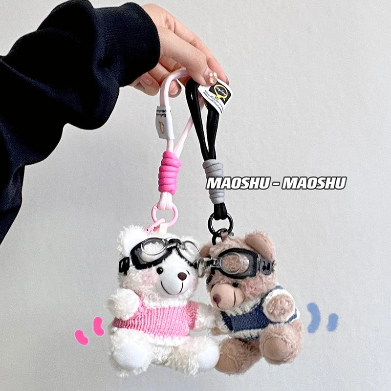A fluffy white bear plush toy with camera and glasses attached to a pink lanyard.
