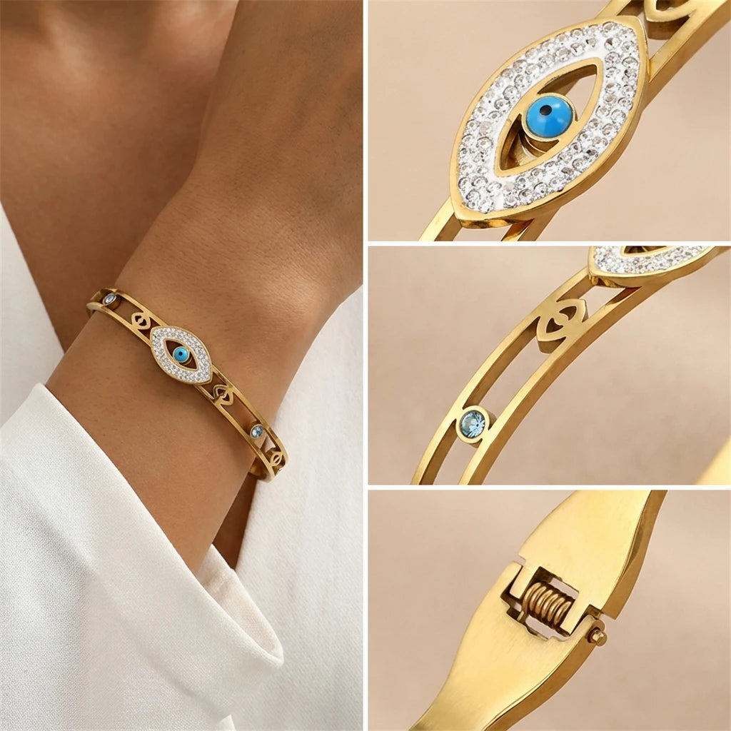 A close-up of a gold cuff bracelet featuring an evil eye crystal design with blue accents.