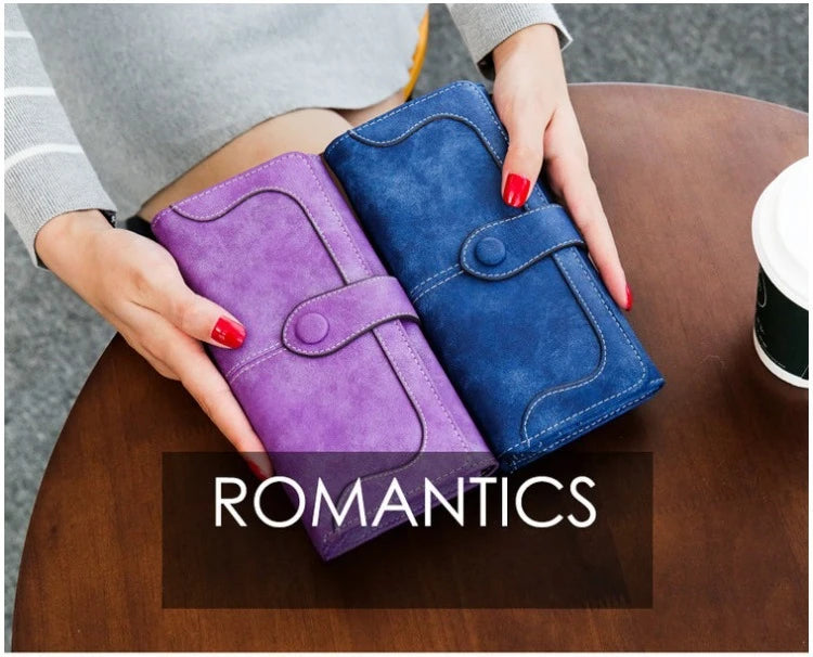A purple and blue clutch wallet is held by a person on a wooden table.