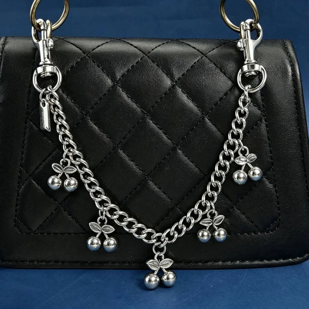 Colgante de cadena plateada en llavero sujeto a un bolso de cuero negro acolchado