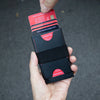 A hand holds a black RFID blocking metal pop-up card wallet with several credit cards.