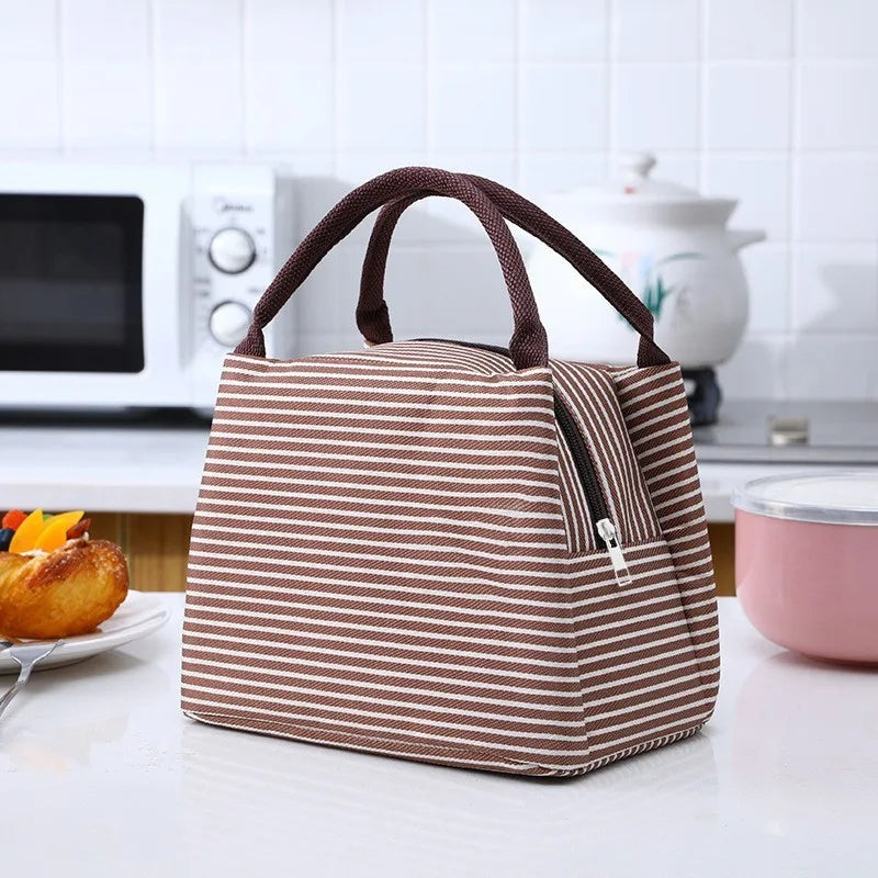 A brown and white striped thermal lunch bag with a handle is placed on a white countertop next to kitchen appliances.