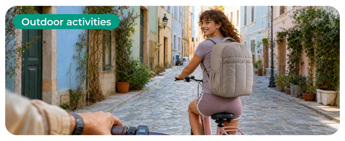 A woman wearing a large capacity laptop backpack is walking down a cobblestone street surrounded by greenery.