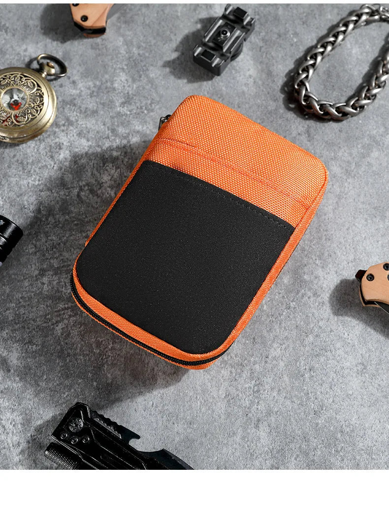 An orange and black fabric pouch designed to organize multi-tools and outdoor gear, shown on a gray surface.