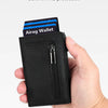 A hand holds a black minimalist magnetic wallet with an Airag Wallet card inside.