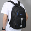 A man is wearing a black lightweight commuter backpack on his back, shown from the rear.