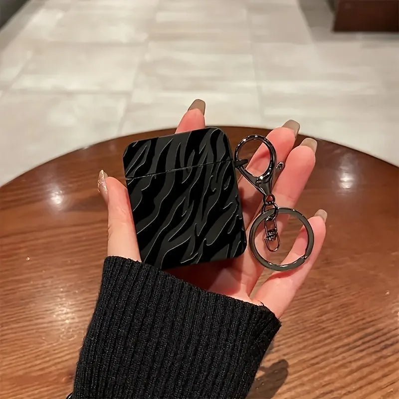 Une main tient une coque de protection à motif zèbre noir pour AirPods Pro avec une chaîne argentée.