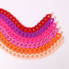 A colorful stack of trendy acrylic statement choker necklaces in various shades of pink, purple, red, and orange.