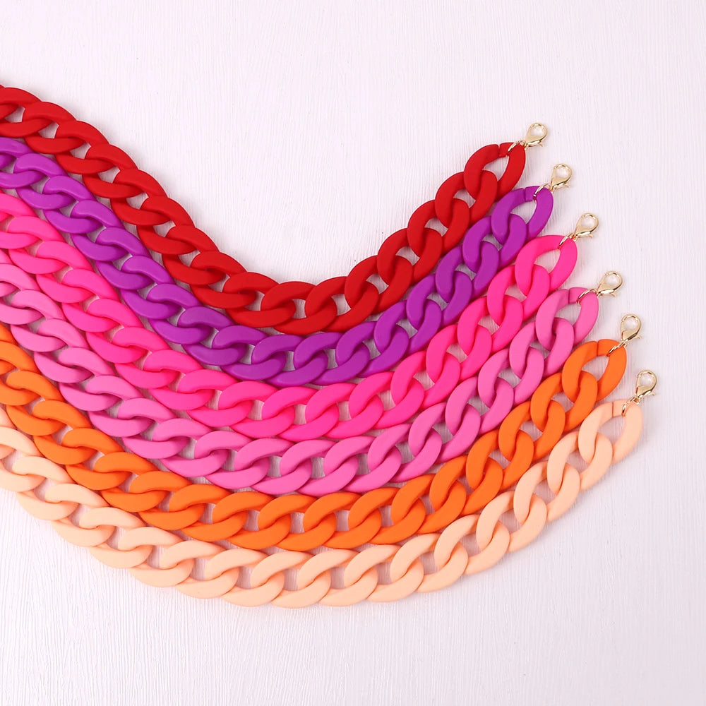 A colorful stack of trendy acrylic statement choker necklaces in various shades of pink, purple, red, and orange.
