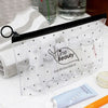 Bolsa de almacenamiento cosmético transparente llena de botellas y tubos de vidrio para viajar.
