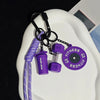 A purple nylon fitness keychain with a bottle attachment and a fitness disc is displayed on a white plate.