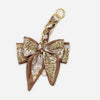 A brown and beige patterned fabric bow with a gold chain strap extension for a handbag.