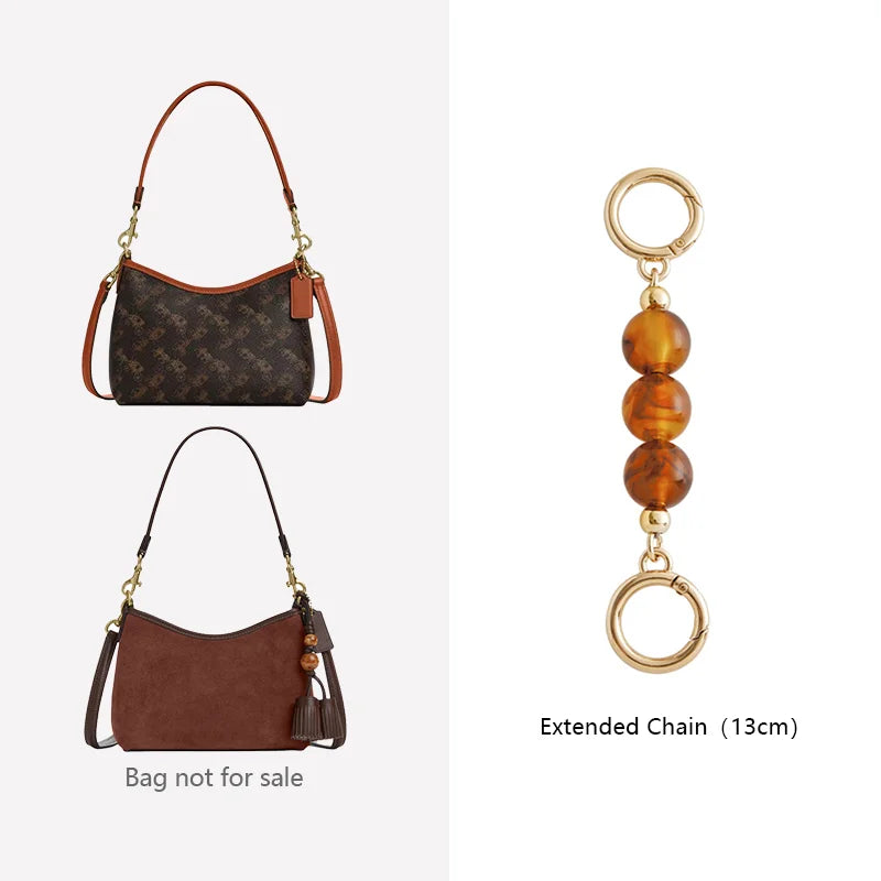 A brown leather crossbody bag with a gold chain and an extended chain accessory.